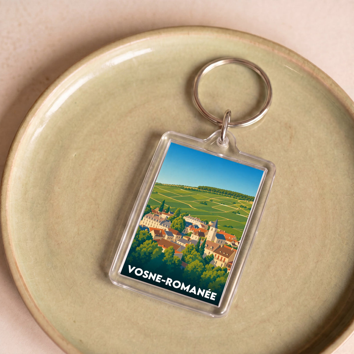 Porte-clés souvenir de la ville de Vosne-Romanée avec une illustration stylisée du village et de ses vignobles.