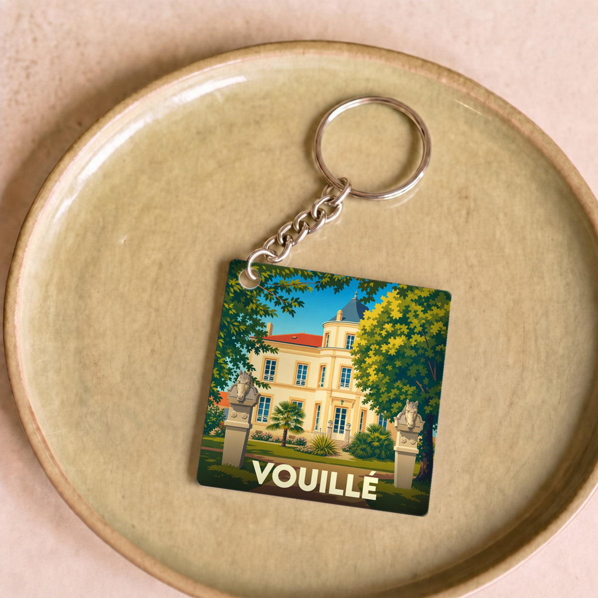 Porte-clés souvenir de la ville de Vouillé avec une illustration stylisée d'un château.