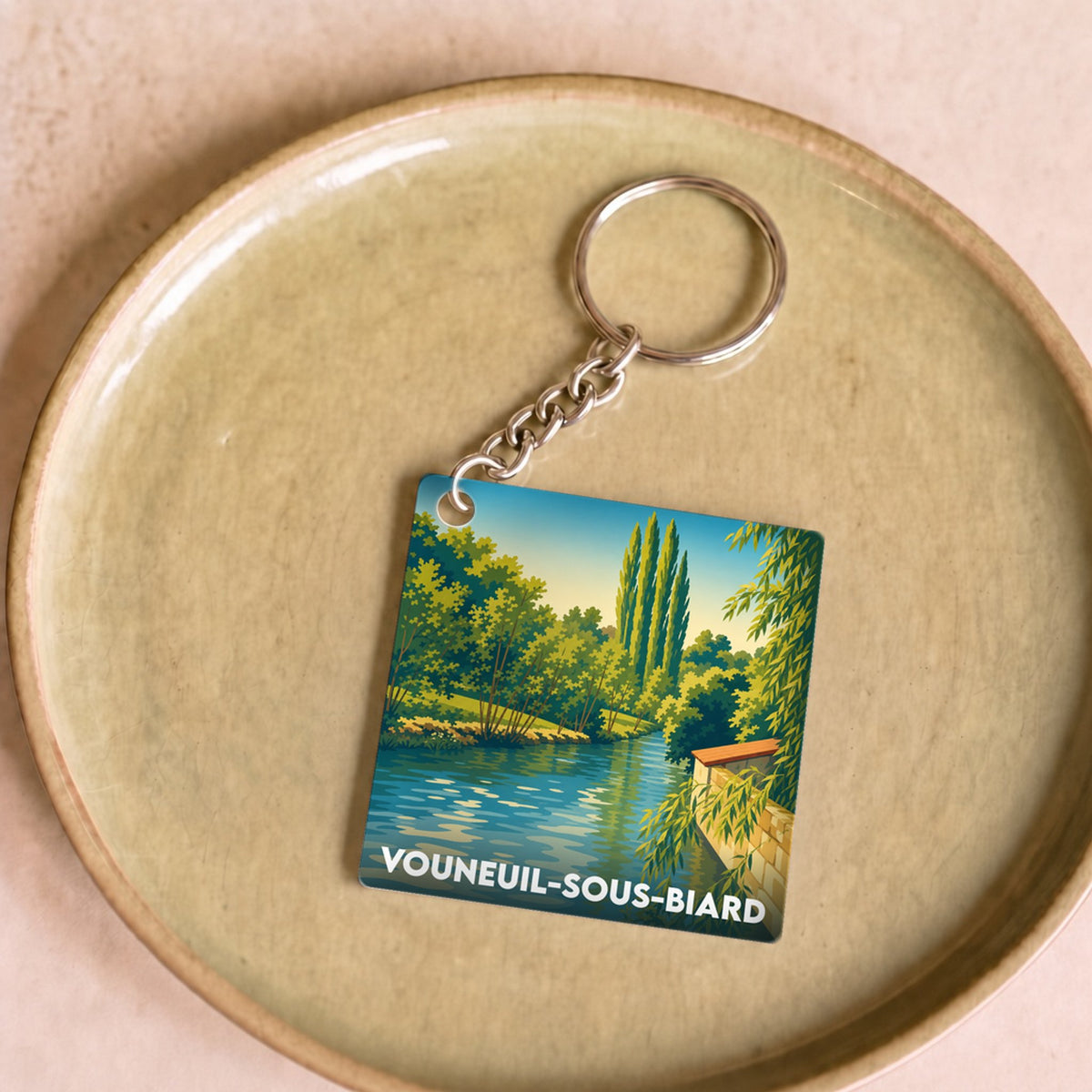 Porte-clés souvenir de la ville de Vouneuil-sous-Biard avec une illustration paysagère stylisée.
