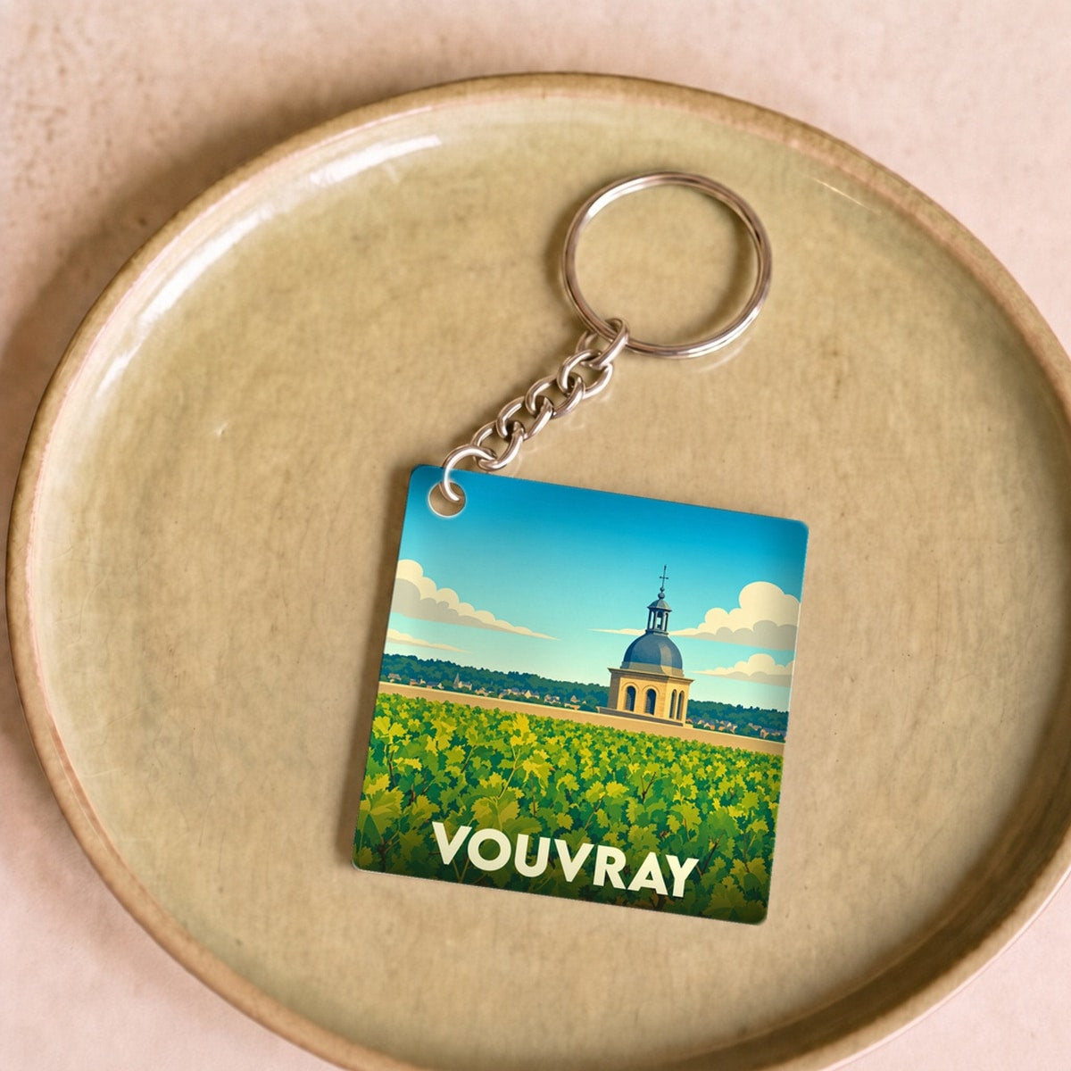 Porte-clés souvenir de la ville de Vouvray avec une illustration stylisée d'un vignoble et d'un monument historique.