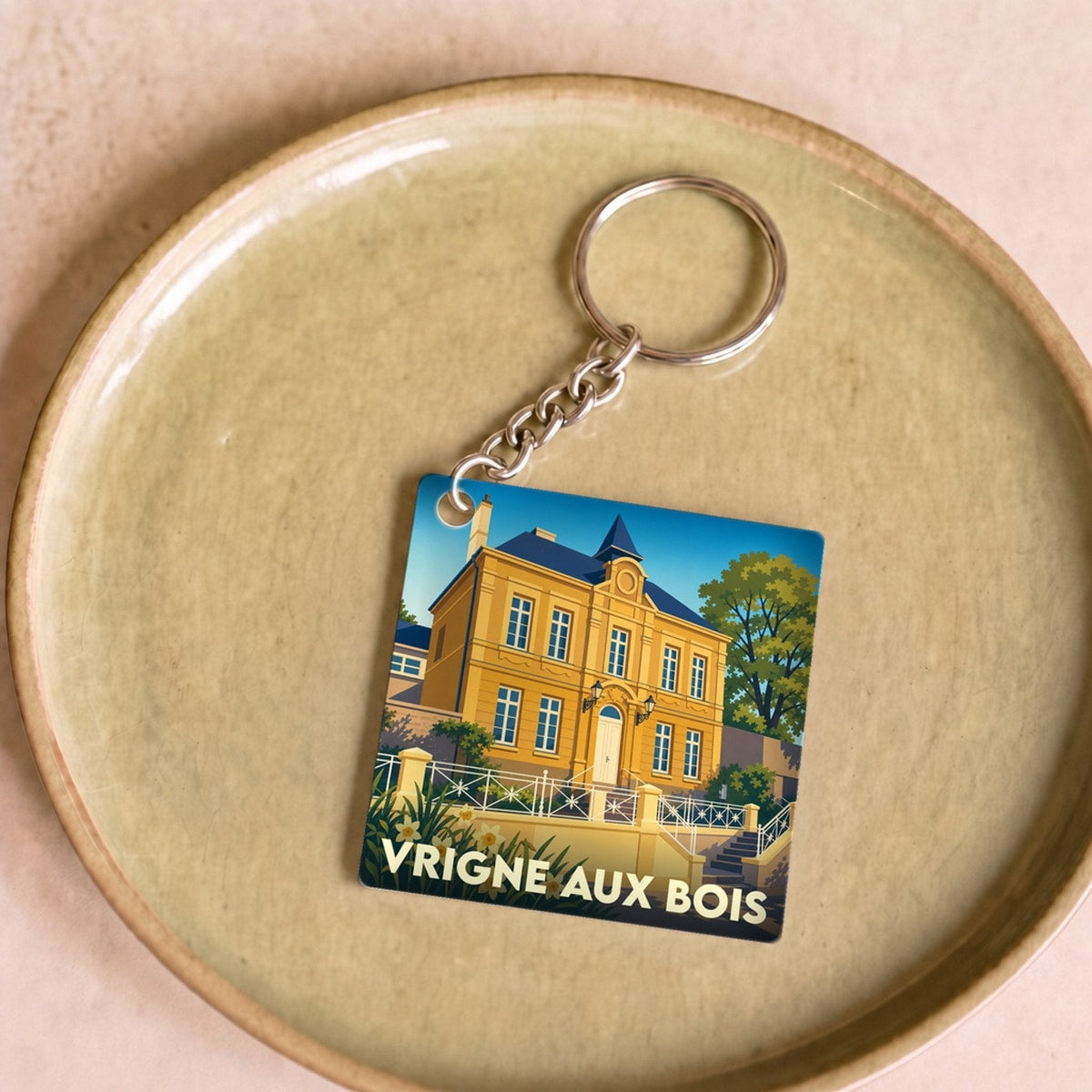 Porte-clés souvenir de la ville de Vrigne aux Bois avec une illustration stylisée d'un bâtiment historique.