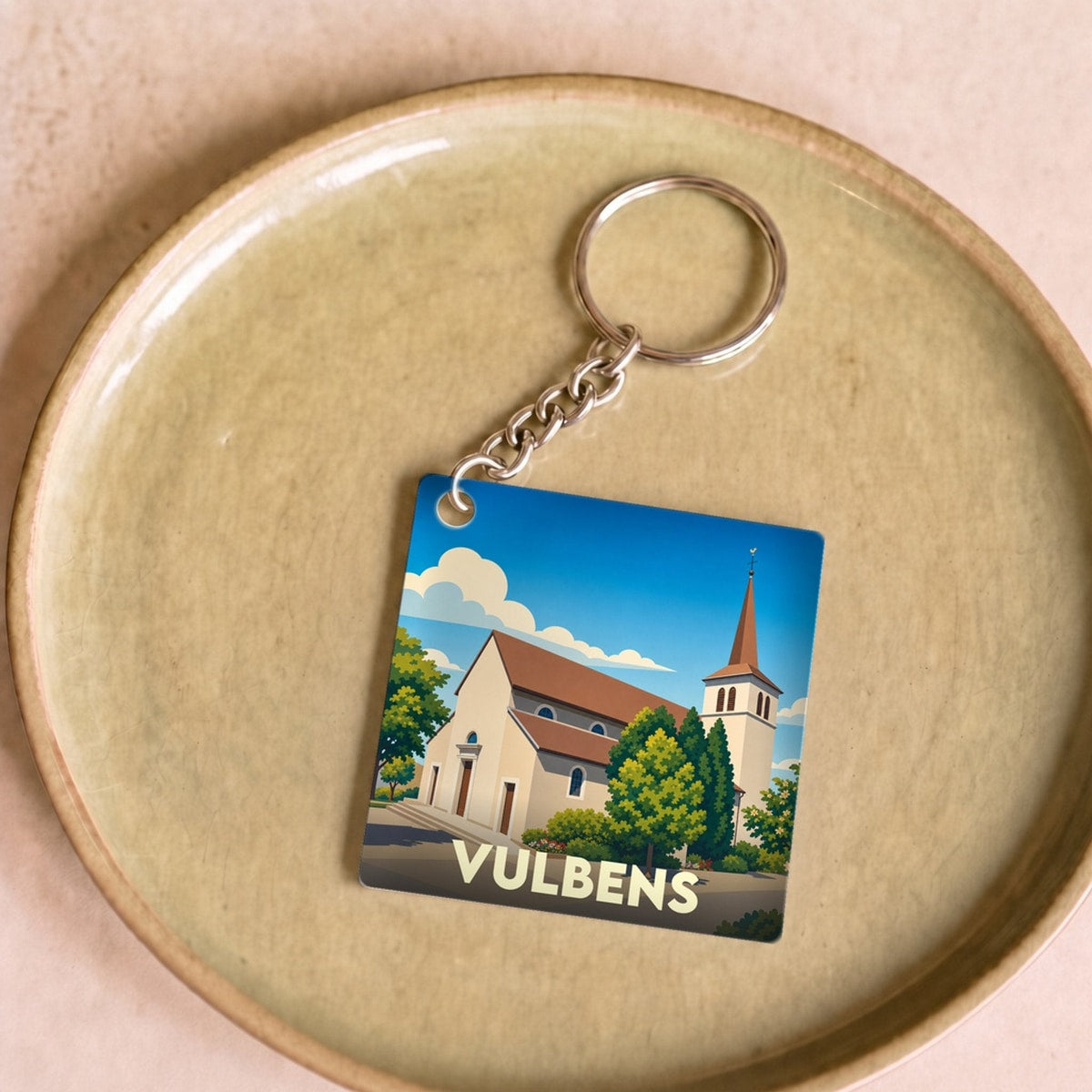 Porte-clés souvenir de la ville de Vulbens avec une illustration stylisée de son église.