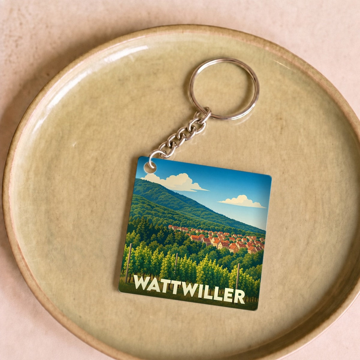Porte-clés souvenir de la ville de Wattwiller avec une illustration stylisée de ses vignobles et montagnes.