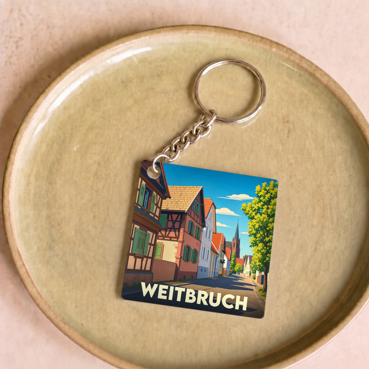 Porte-clés souvenir de la ville de Weitbruch avec une illustration stylisée de ses maisons à colombages.