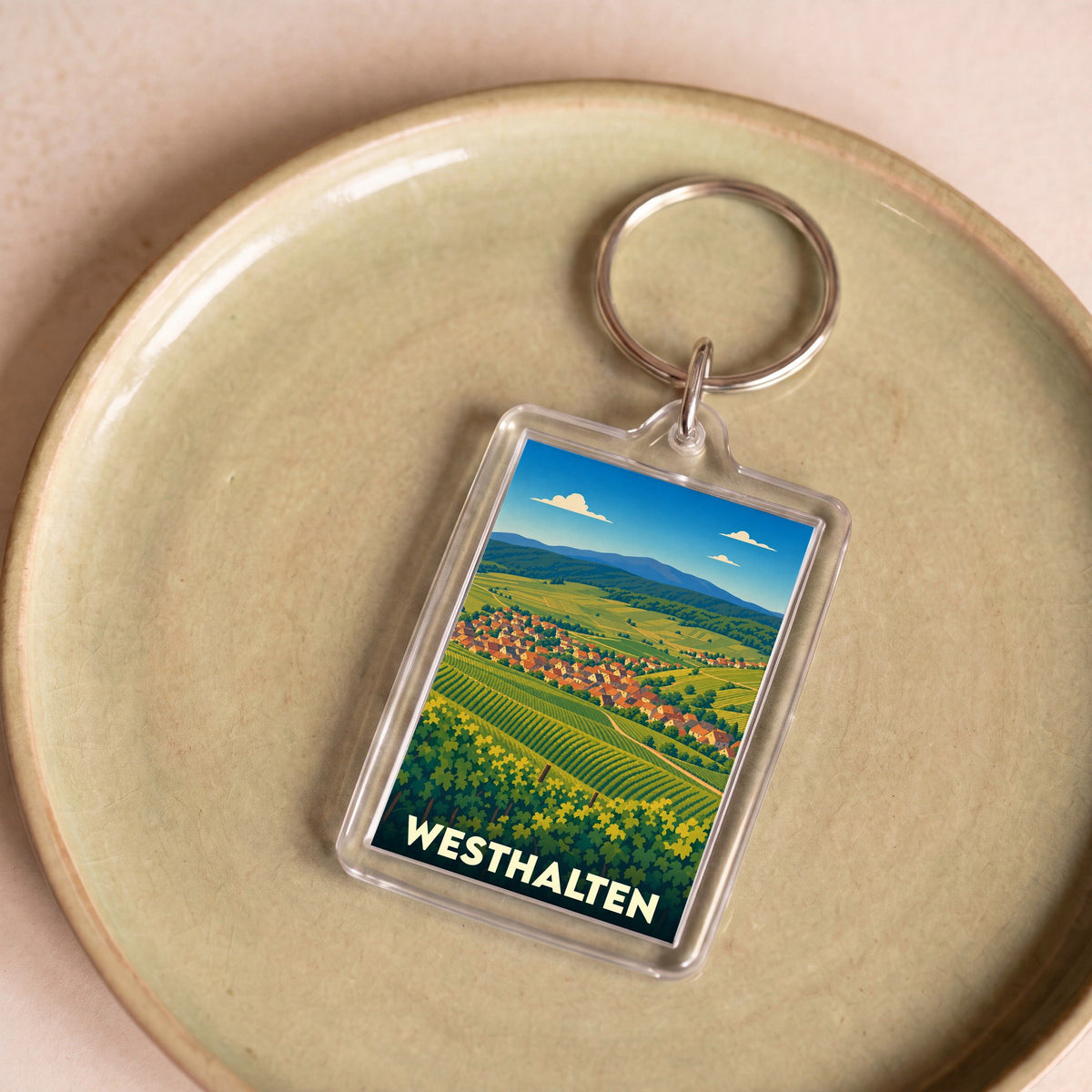 Porte-clés souvenir de la ville de Westhalten avec une illustration stylisée de son vignoble et de son village.