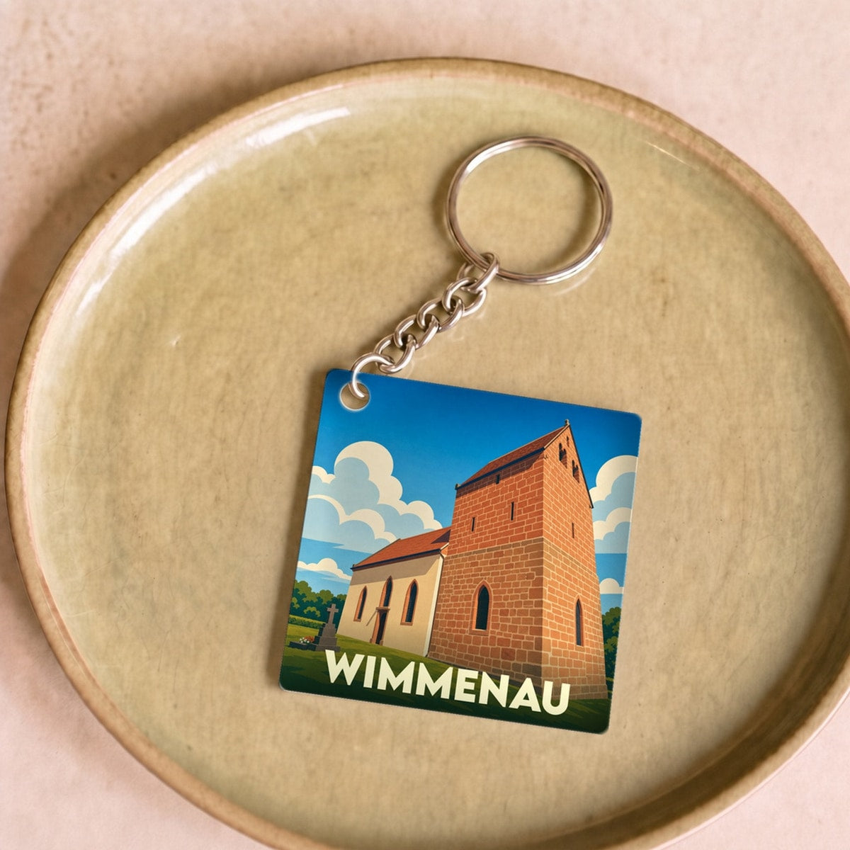 Porte-clés souvenir de la ville de Wimmenau avec une illustration stylisée d'une église sur fond de ciel bleu.