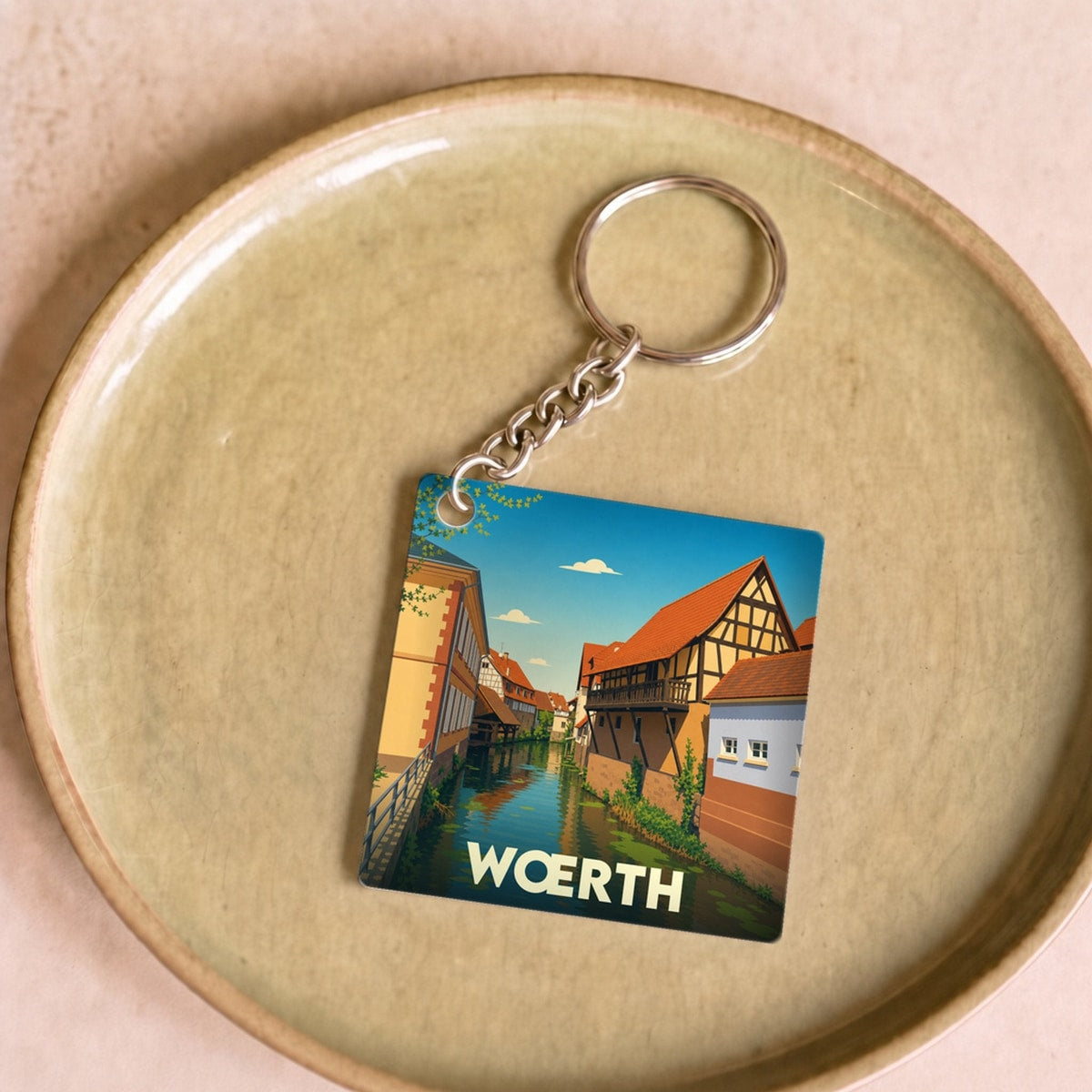 Porte-clés souvenir de la ville de Wœrth avec une illustration stylisée d'un canal bordé de maisons à colombages.