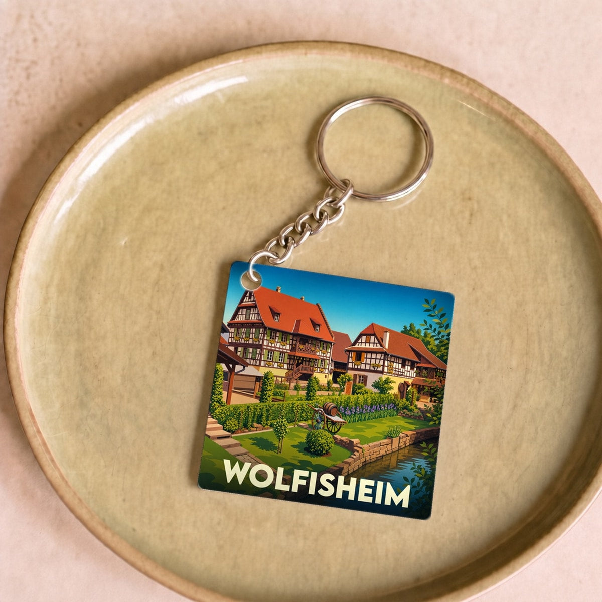 Porte-clés souvenir de la ville de Wolfisheim avec une illustration stylisée de maisons à colombages au bord de l'eau.