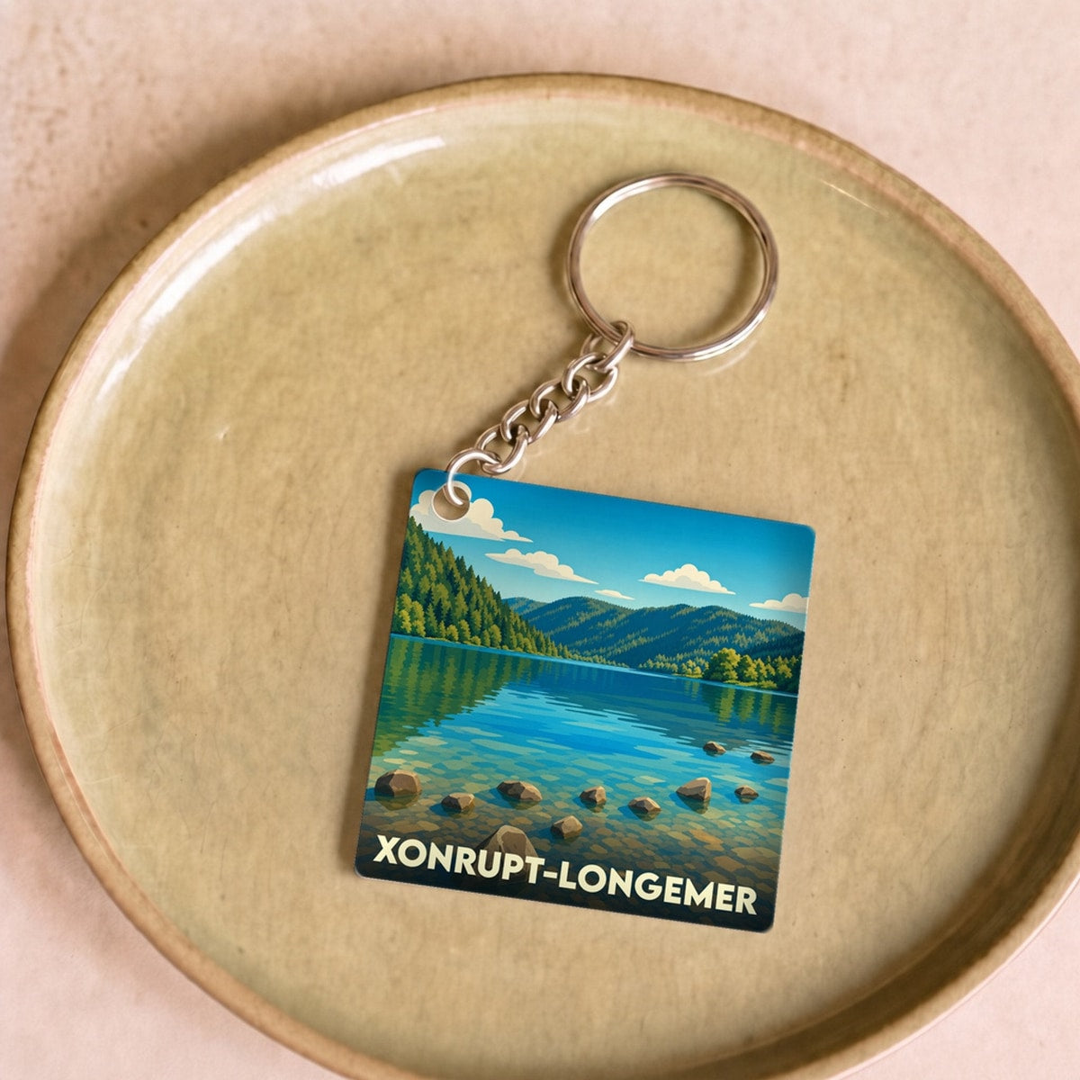 Porte-clés souvenir de la ville de Xonrupt-Longemer avec une illustration stylisée d'un lac de montagne.