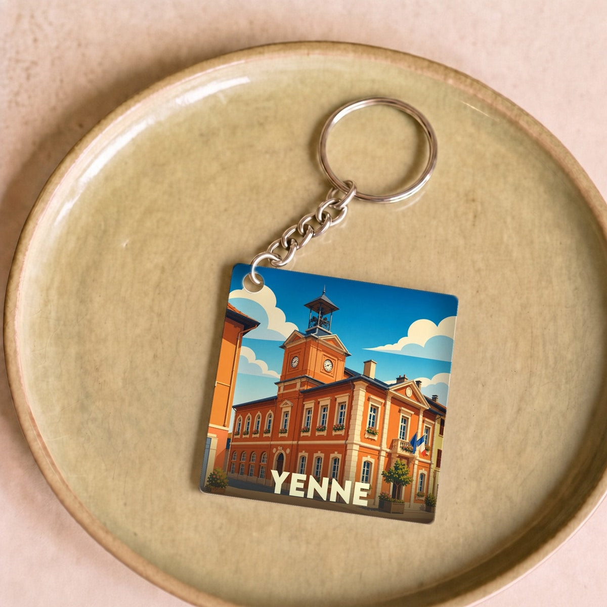 Porte-clés souvenir de la ville de Yenne avec une illustration stylisée de son architecture.