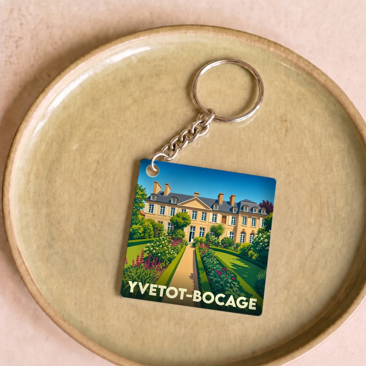 Porte-clés souvenir de la ville d'Yvetot-Bocage avec une illustration stylisée d'un château et de ses jardins.