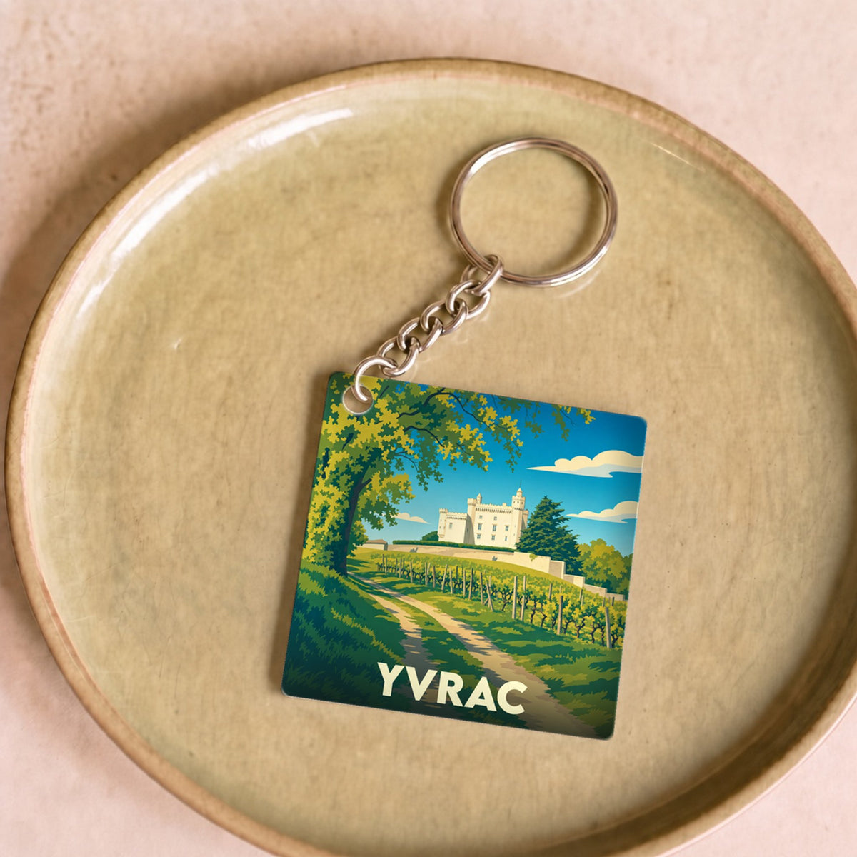 Porte-clés souvenir de la ville d'Yvrac avec une illustration stylisée d'un château et de vignobles.