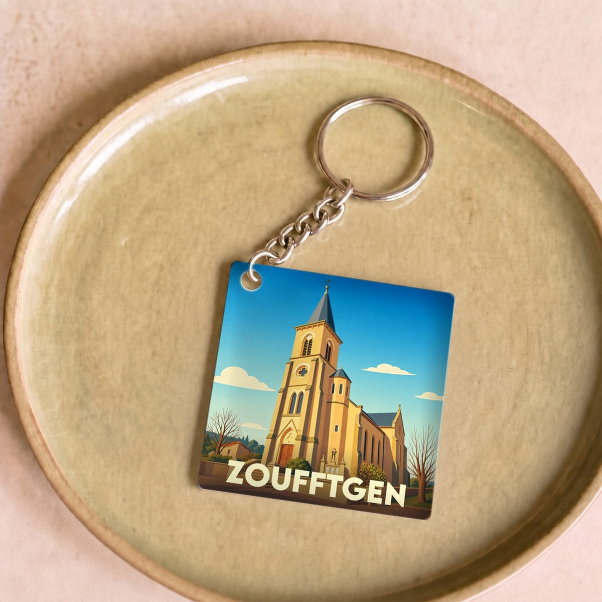 Porte-clés souvenir de la ville de Zoufftgen avec une illustration stylisée de son église.