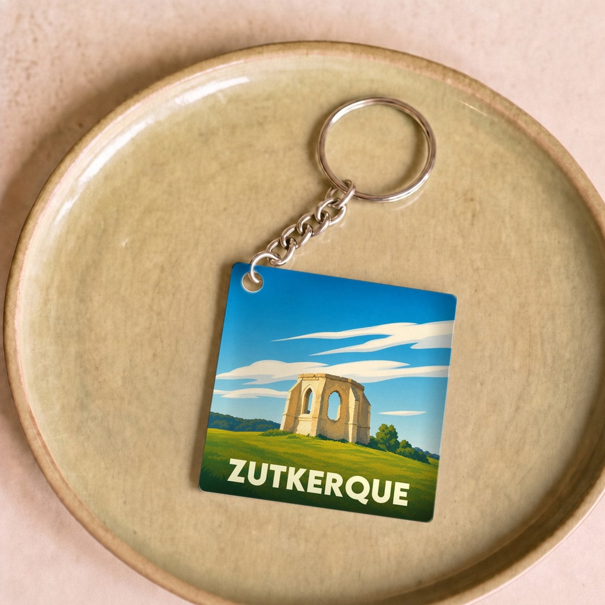 Porte-clés souvenir de la ville de Zutkerque avec une illustration stylisée de ruines historiques.