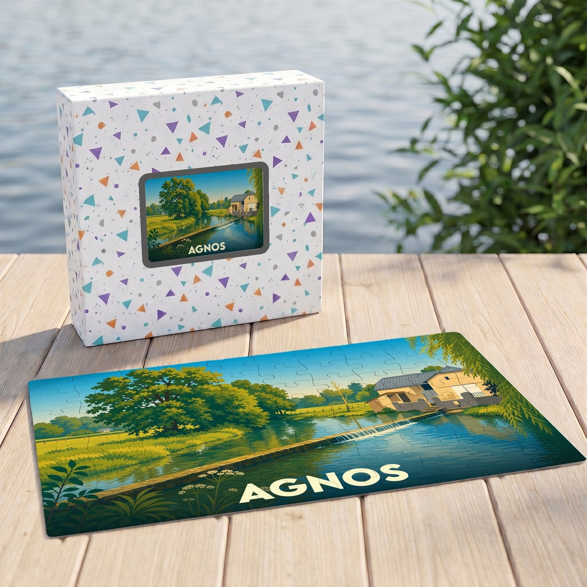 Puzzle souvenir de la ville d'Agnos avec une illustration de paysage champêtre au bord de l'eau.