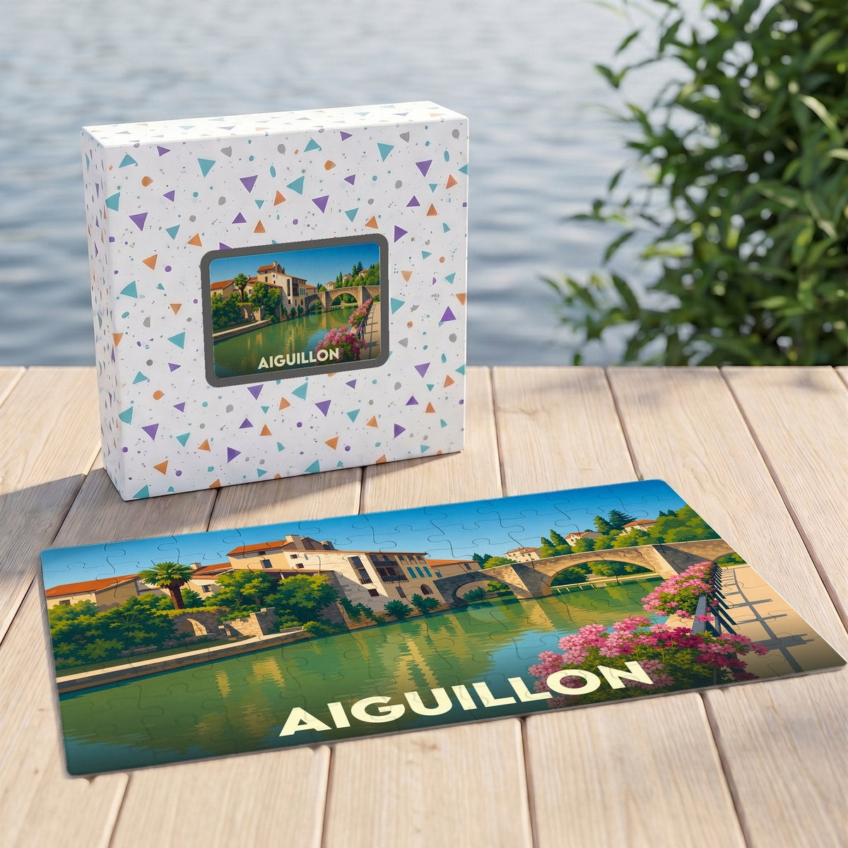 Puzzle souvenir de la ville d'Aiguillon présentant une illustration stylisée d'un pont et de maisons au bord de l'eau.