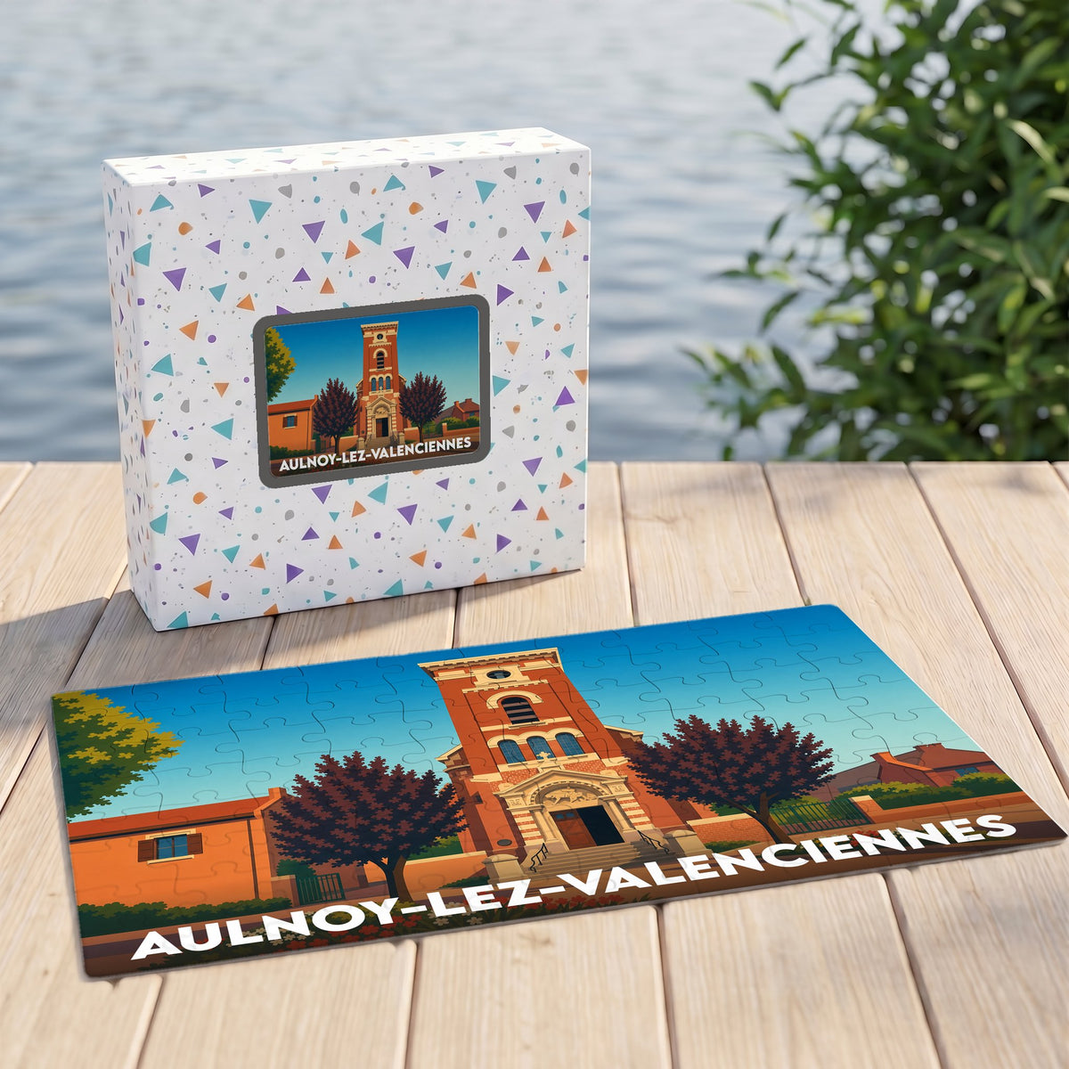 Puzzle souvenir de la ville d'Aulnoy-lez-Valenciennes illustré par une vue stylisée de son église, présenté avec sa boîte assortie.
