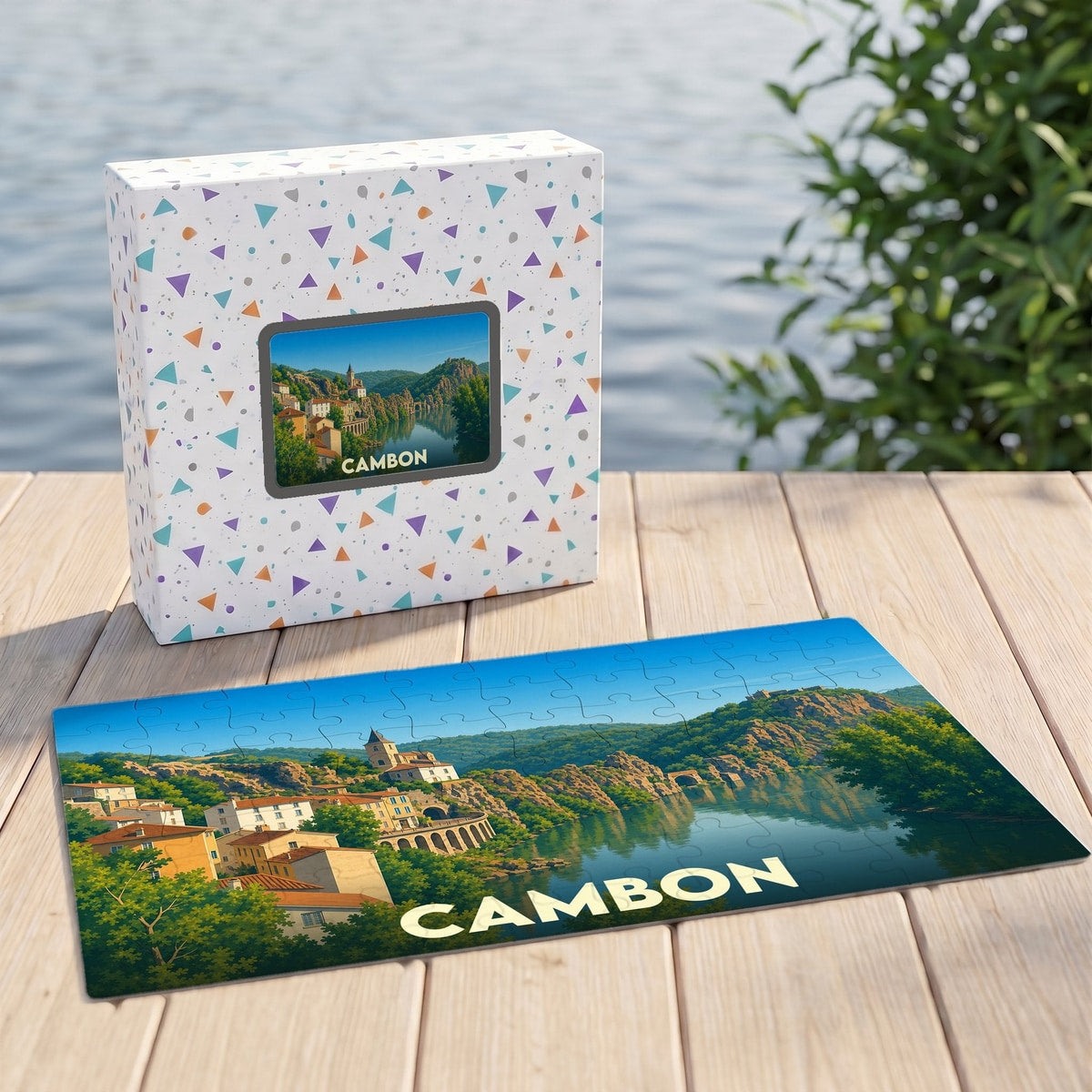 Puzzle souvenir de la ville de Cambon représentant un paysage ensoleillé au bord de l'eau.