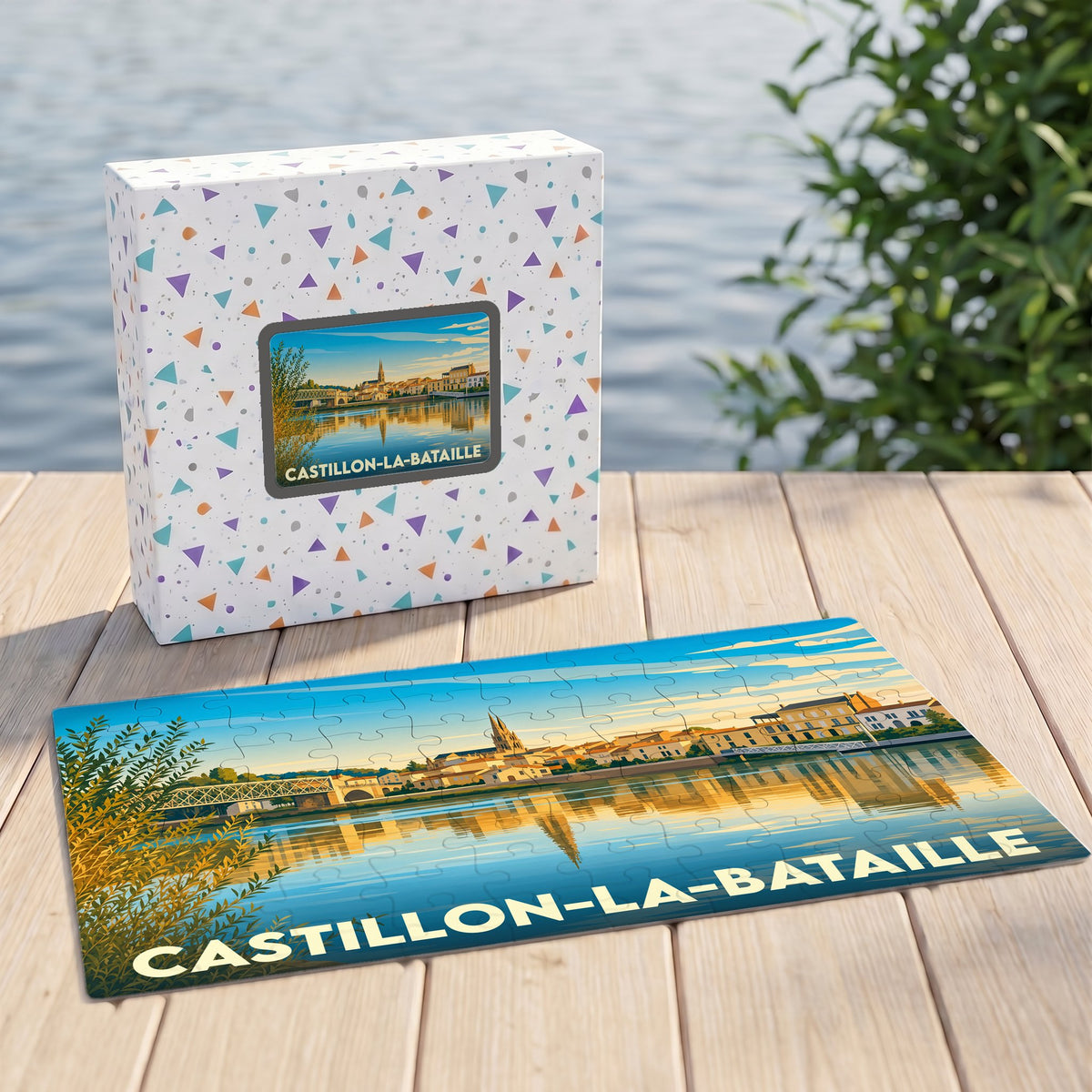 Puzzle souvenir de la ville de Castillon-la-Bataille avec son coffret illustré d'un paysage urbain stylisé au bord de l'eau.