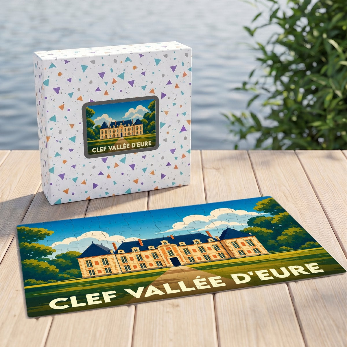 Puzzle souvenir de Clef Vallée d'Eure illustrant un château stylisé, présenté avec sa boîte assortie sur un ponton en bois.