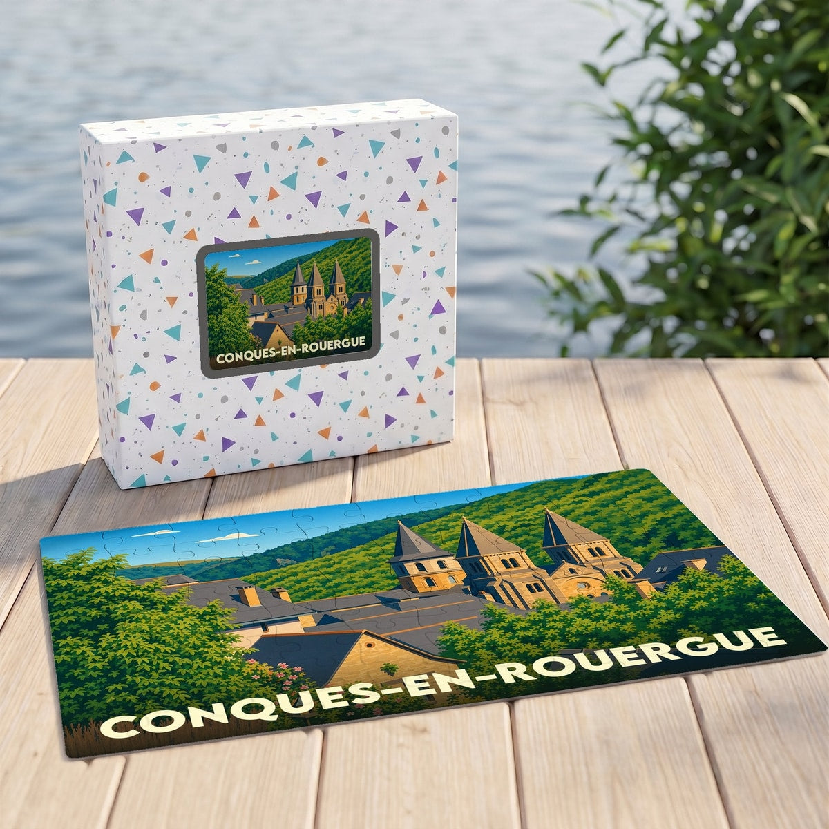 Puzzle souvenir de la ville de Conques-en-Rouergue avec une illustration stylisée de son abbaye et de son paysage vallonné.
