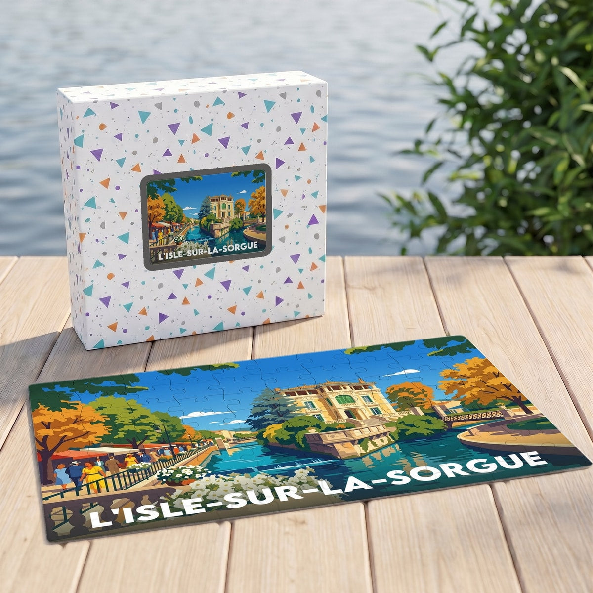 Puzzle souvenir de la ville de L'Isle-sur-la-Sorgue avec une illustration colorée et stylisée d'un canal bordé de bâtiments.