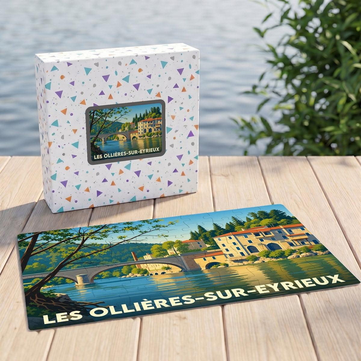 Puzzle souvenir de la ville de Les Ollières-sur-Eyrieux avec une illustration stylisée de son pont et de ses maisons au bord de l'eau.