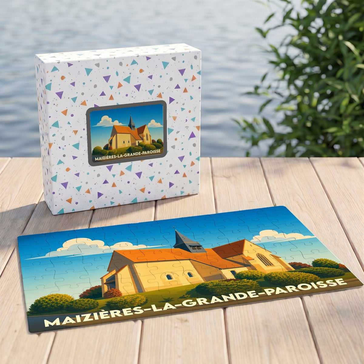 Puzzle souvenir de Maizières-la-Grande-Paroisse représentant son église dans un style illustré, posé à côté de sa boîte assortie.