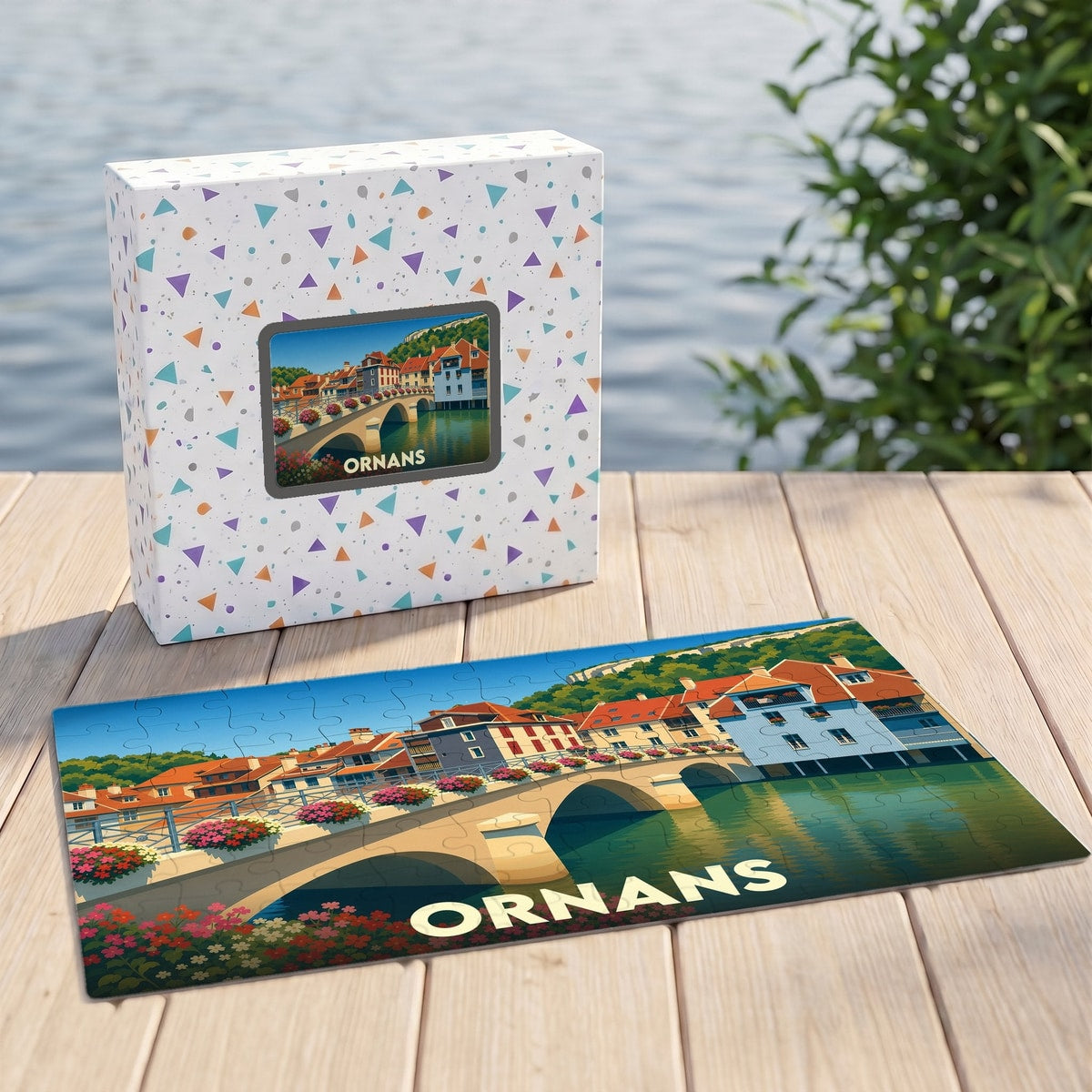 Puzzle souvenir de la ville d'Ornans illustrant un pont et des maisons colorées au bord de l'eau.