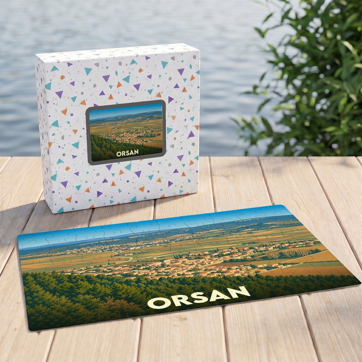 Puzzle souvenir de la ville d'Orsan présentant une illustration panoramique stylisée dans sa boîte assortie.