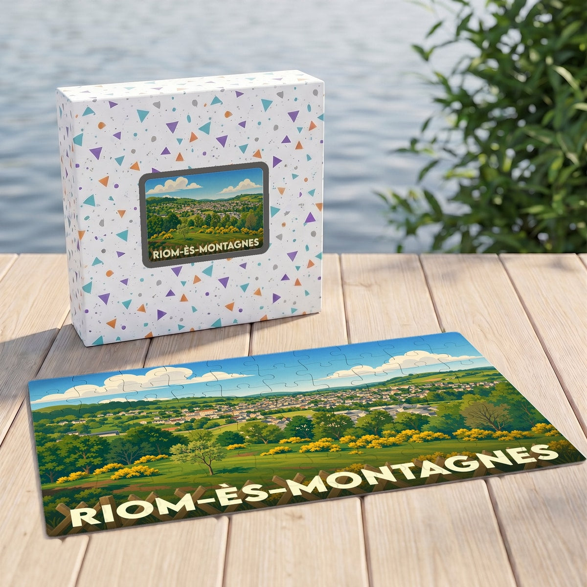 Puzzle souvenir de la ville de Riom-ès-Montagnes avec une illustration paysagère stylisée.