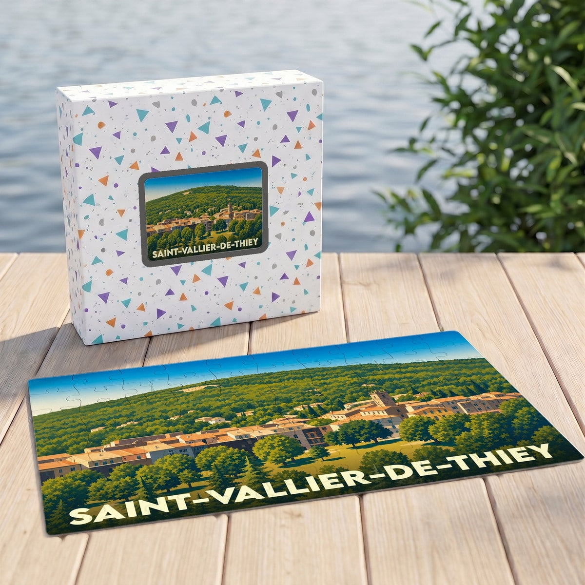 Puzzle souvenir de la ville de Saint-Vallier-de-Thiey avec son coffret assorti, présentant une illustration stylisée d'un village provençal.