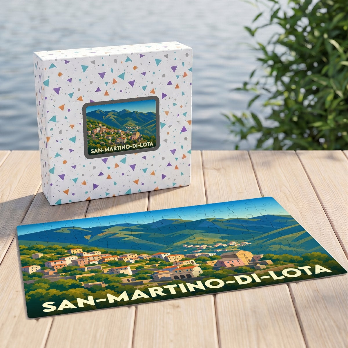 Puzzle souvenir de la ville de San-Martino-di-Lota avec son boîte, présentant une illustration stylisée d'un village corse à flanc de montagne.