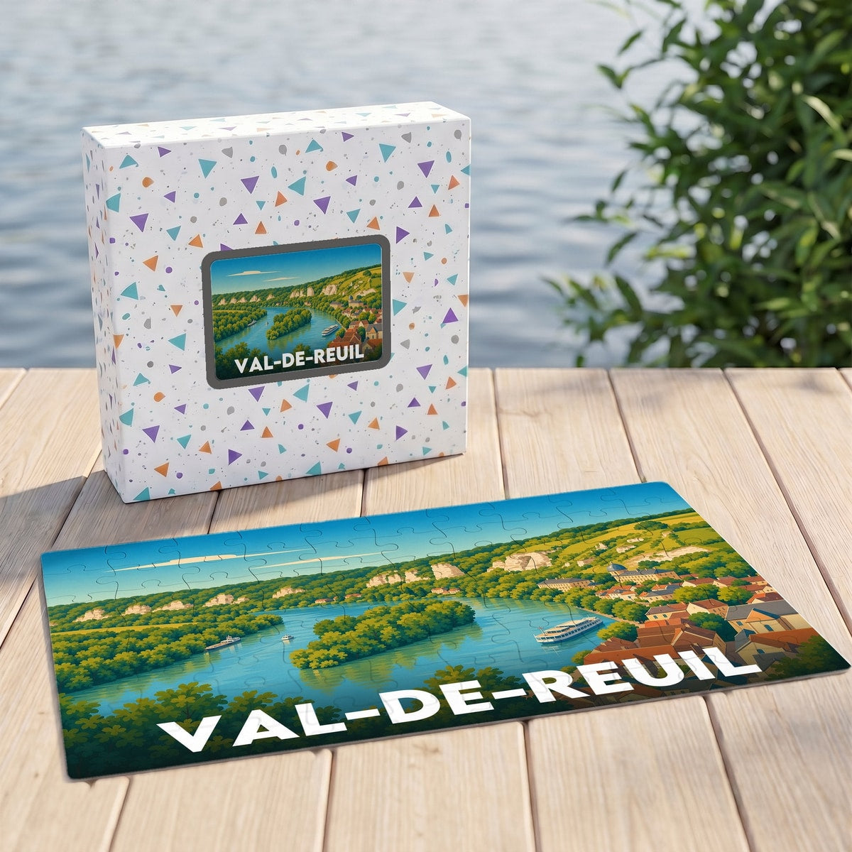 Puzzle souvenir de la ville de Val-de-Reuil avec son boîte assortie, illustrant un paysage fluvial stylisé.