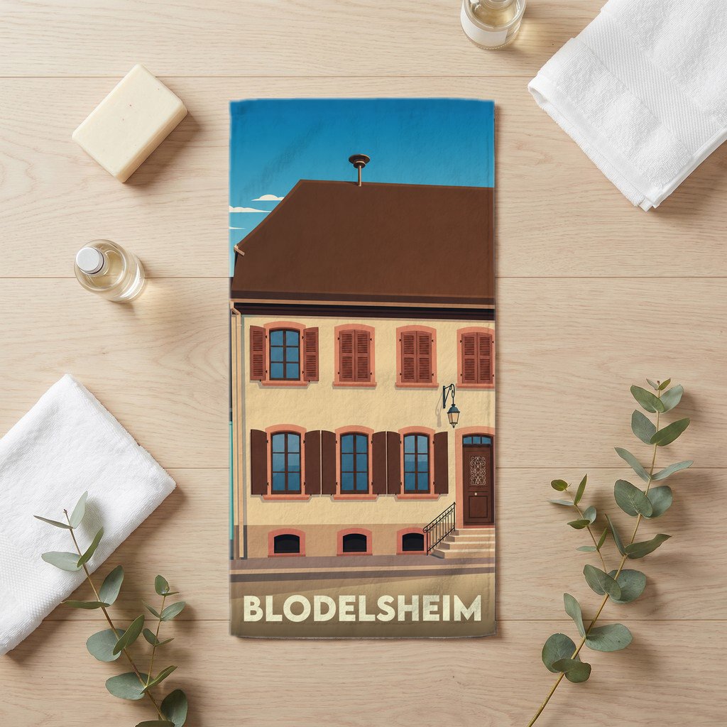 Serviette de bain souvenir de la ville de Blodelsheim avec une illustration stylisée d'un bâtiment traditionnel.