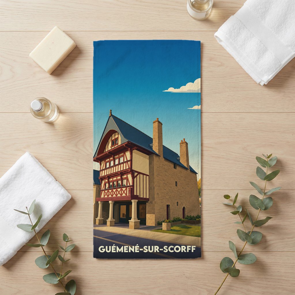 Serviette de bain souvenir de la ville de Guémené-sur-Scorff avec une illustration stylisée d'une maison à colombages.