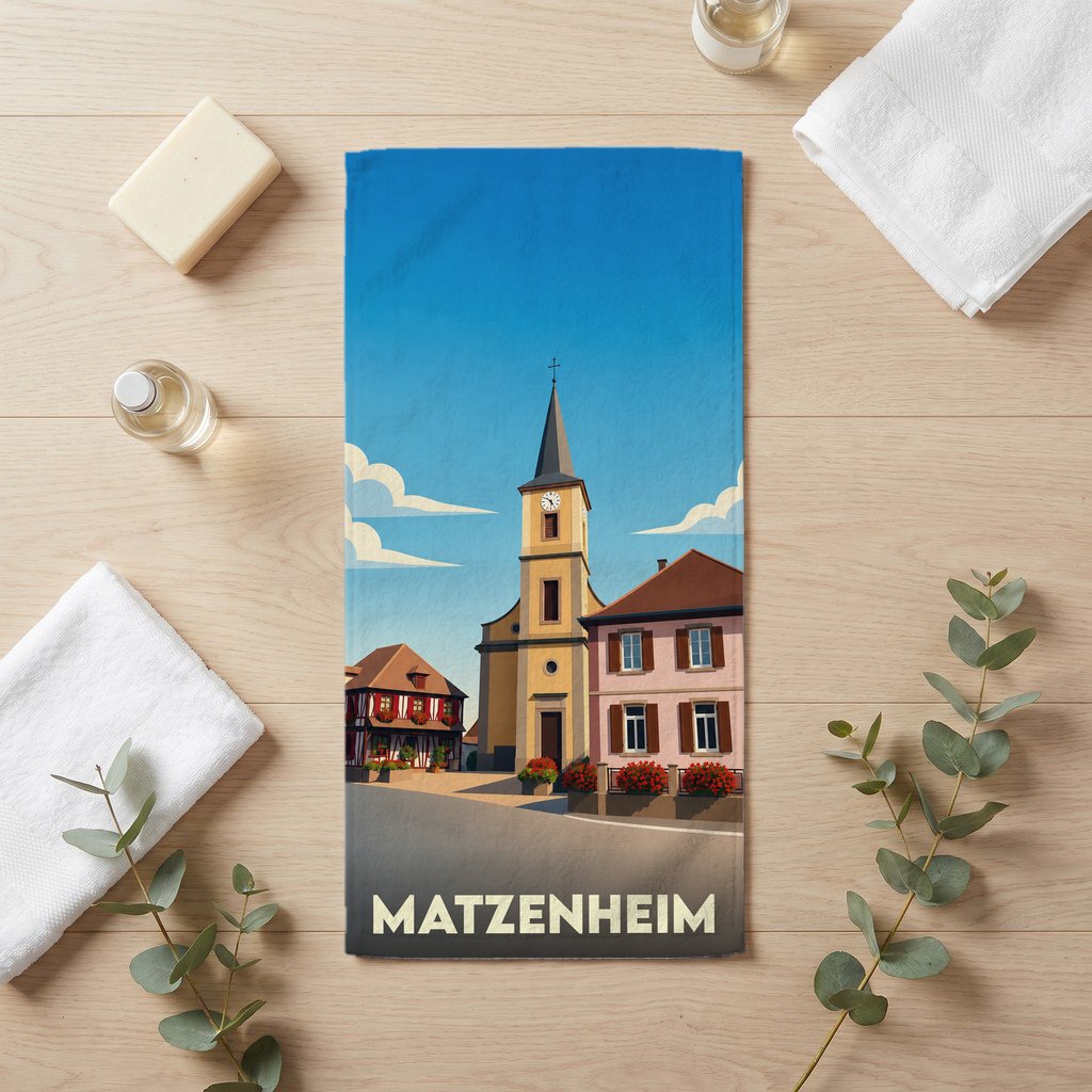 Serviette de bain souvenir de la ville de Matzenheim avec une illustration stylisée d'une église et de maisons à colombages.