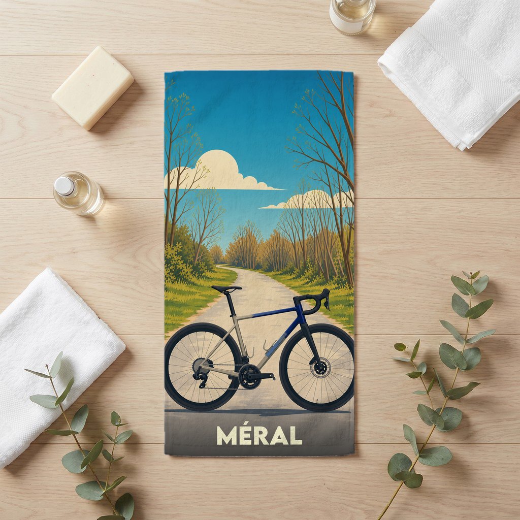 Serviette de bain souvenir de la ville de Méral illustrée d'un vélo sur une route de campagne.