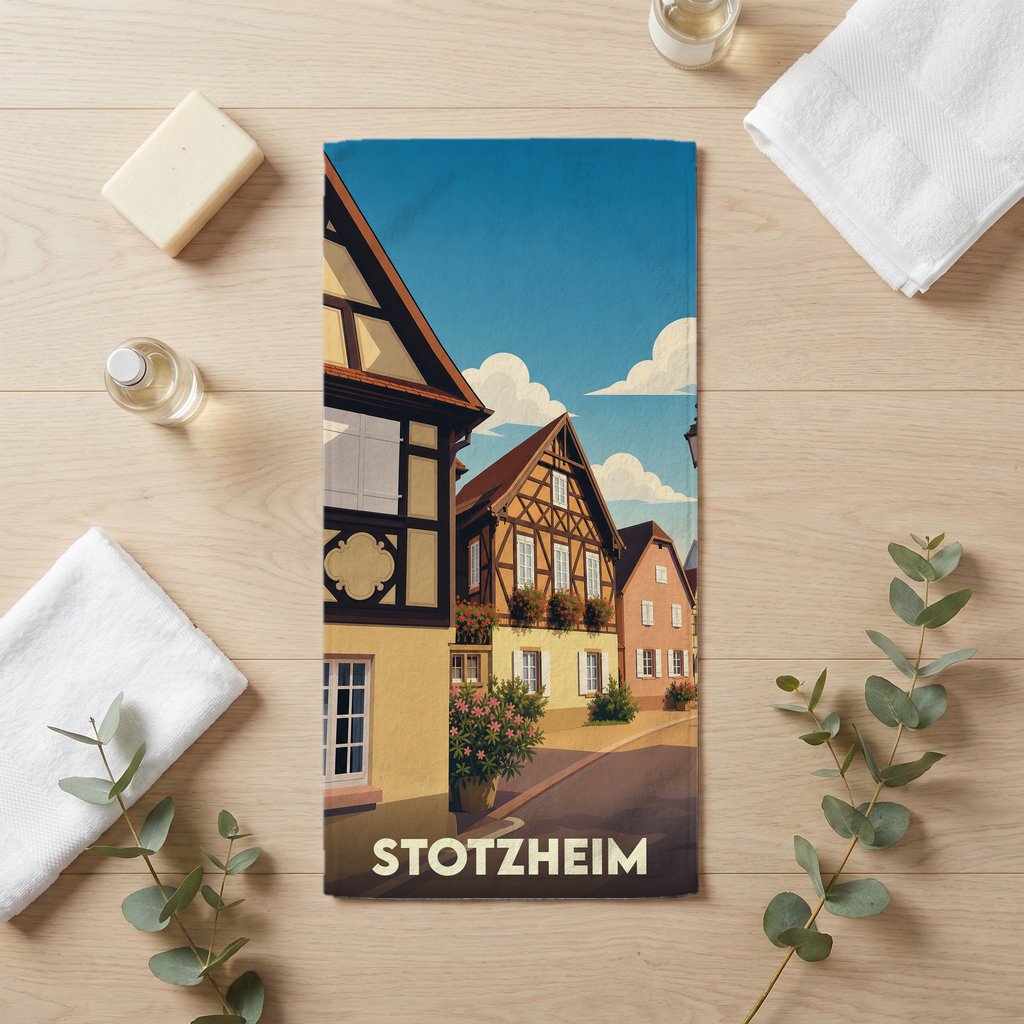 Serviette de bain souvenir de la ville de Stotzheim avec une illustration stylisée de maisons à colombages.
