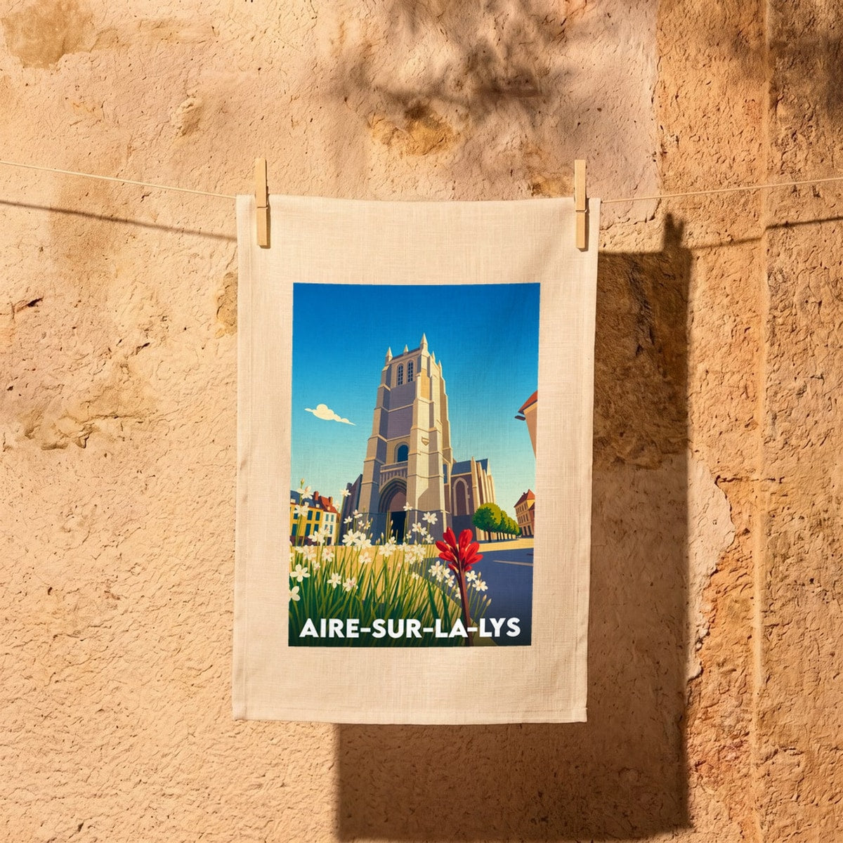 Torchon souvenir de la ville d'Aire-sur-la-Lys avec une illustration stylisée de son église et de son centre historique.