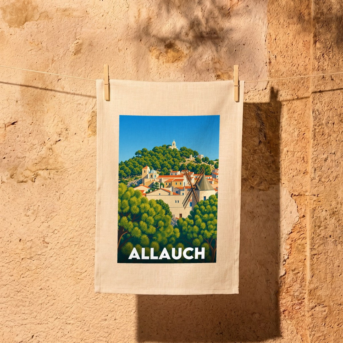 Torchon souvenir de la ville d'Allauch avec une illustration stylisée du village et de son moulin.