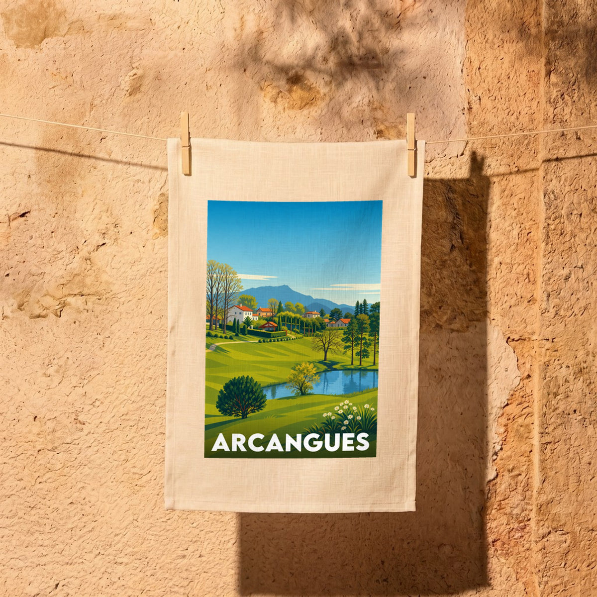 Torchon souvenir de la ville d'Arcangues avec une illustration de paysage stylisée.