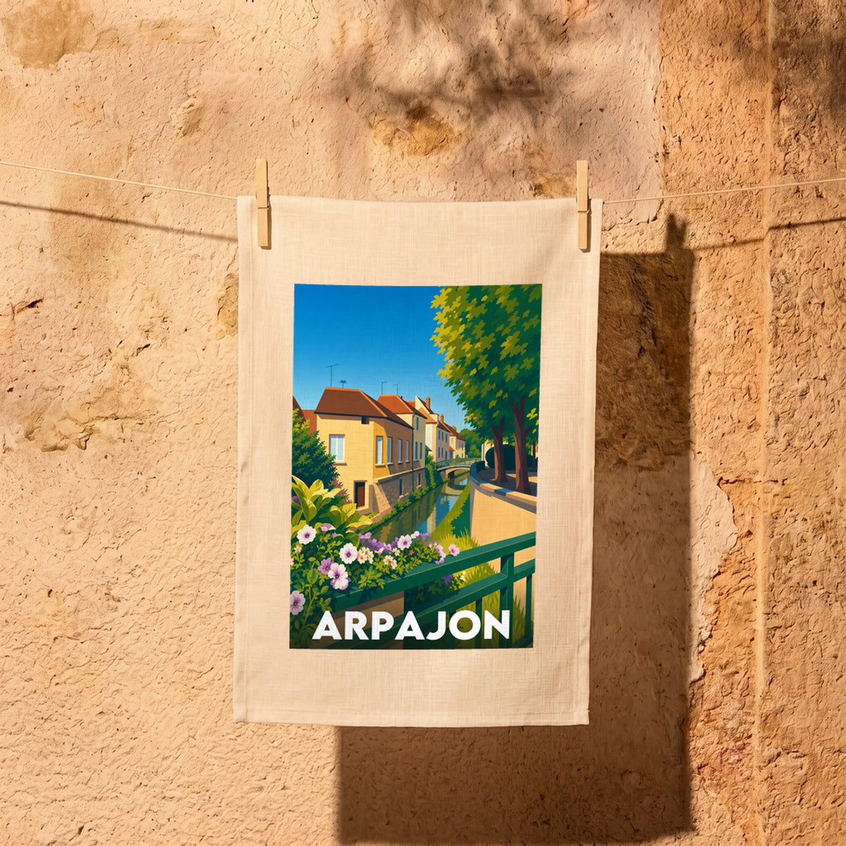 Torchon souvenir de la ville d'Arpajon avec une illustration stylisée d'un canal bordé de maisons.