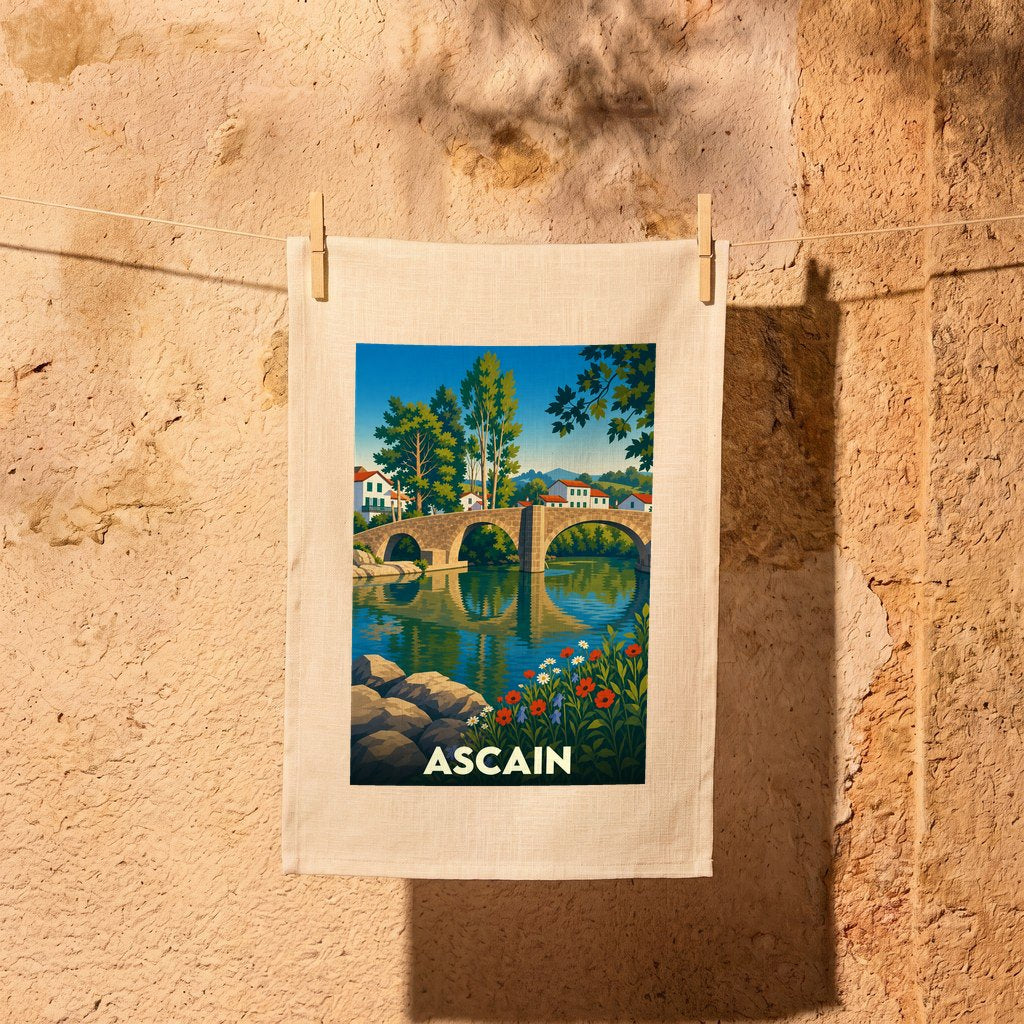 Torchon souvenir de la ville d'Ascain avec une illustration stylisée représentant son pont médiéval et la rivière.