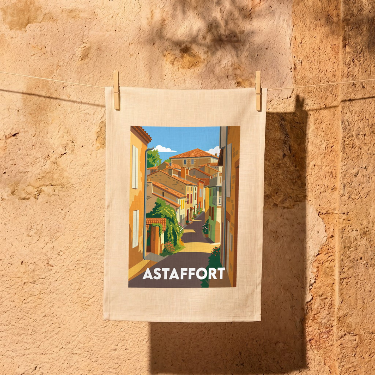 Torchon souvenir de la ville d'Astaffort avec une illustration stylisée de ses rues colorées.