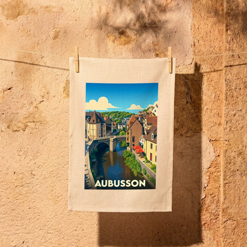 Torchon souvenir de la ville d'Aubusson orné d'une illustration stylisée représentant son pont et ses maisons au bord de l'eau.