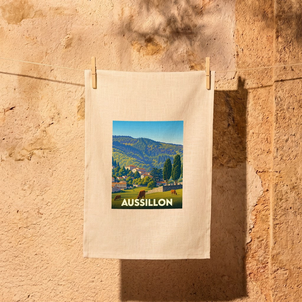Torchon souvenir de la ville de Aussillon avec une illustration stylisée d'un paysage de campagne.