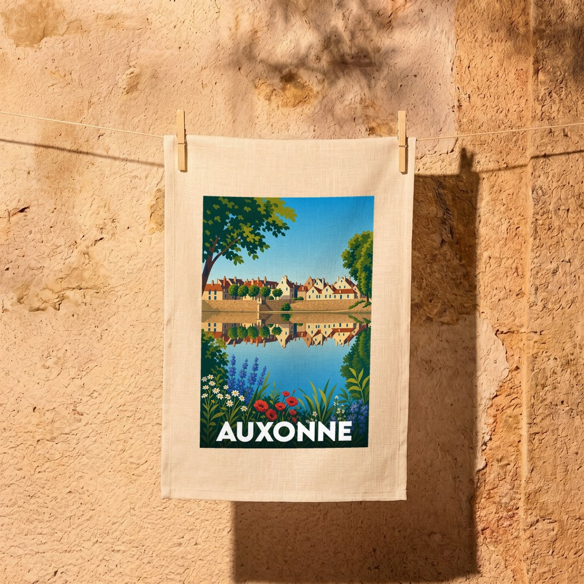 Torchon souvenir de la ville d'Auxonne avec une illustration stylisée d'un paysage urbain se reflétant dans l'eau.