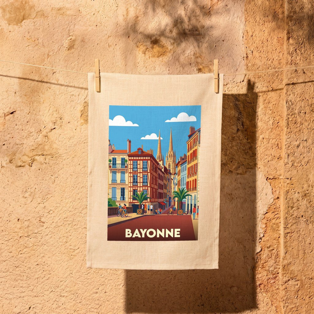 Torchon souvenir de la ville de Bayonne avec une illustration stylisée de ses bâtiments colorés et de sa cathédrale.