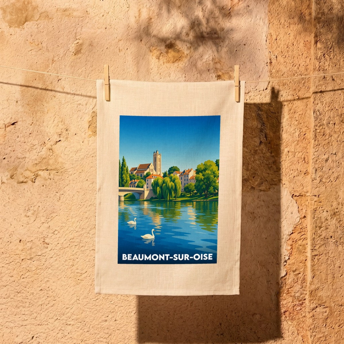 Torchon souvenir de Beaumont-sur-Oise illustrant un paysage de bord de rivière avec son église et son pont.